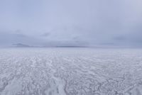 a picture of an overcast sky over a vast plain of snow with a large mountain in the distance