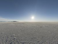 the sun is setting on a snow field in the distance to the right of the camera