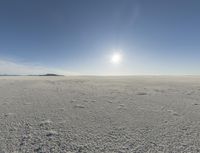 the sun is setting on a snow field in the distance to the right of the camera