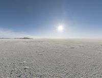 the sun is setting on a snow field in the distance to the right of the camera