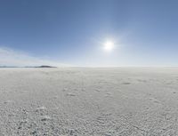 the sun is setting on a snow field in the distance to the right of the camera