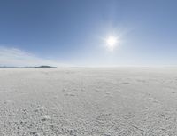 the sun is setting on a snow field in the distance to the right of the camera