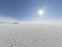 the sun is setting on a snow field in the distance to the right of the camera