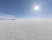 the sun is setting on a snow field in the distance to the right of the camera