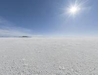 the sun is setting on a snow field in the distance to the right of the camera