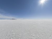 the sun is setting on a snow field in the distance to the right of the camera