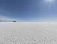 the sun is setting on a snow field in the distance to the right of the camera