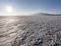 the sun shines brightly over a snow filled expanse with rocks and mountains in the background