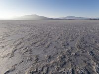 the sun shines brightly over a snow filled expanse with rocks and mountains in the background