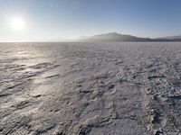 the sun shines brightly over a snow filled expanse with rocks and mountains in the background