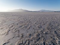the sun shines brightly over a snow filled expanse with rocks and mountains in the background