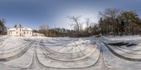 snow covered street in the middle of a wooded area with trees behind it and a house