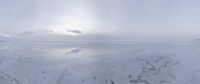 a man walking along a large ice covered beach near mountains under a cloudy sky,