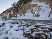 a person riding on the back of a motorcycle down a road covered in snow next to a cliff