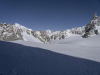 a lone skier is skiing through the snow in front of mountains under a clear blue sky