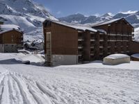 a mountain resort in the winter surrounded by snow and a house with skis on the slope