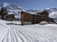 a mountain resort in the winter surrounded by snow and a house with skis on the slope