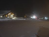 a snow covered park area at night with buildings and trees on the other side of it