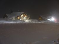 a snow covered park area at night with buildings and trees on the other side of it