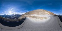 a panoramic image of some people in the snow on a hill near mountains