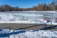 a pond with snow on the ground and a brick path near it and a sign pointing to the water