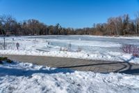 a pond with snow on the ground and a brick path near it and a sign pointing to the water