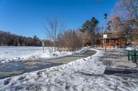 a park with benches, trees and water along the ice covered path that runs into a gazebo