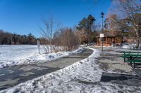 a park with benches, trees and water along the ice covered path that runs into a gazebo