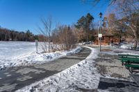 a park with benches, trees and water along the ice covered path that runs into a gazebo