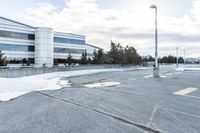 a parking lot covered in snow near a building, and people walking with backpacks