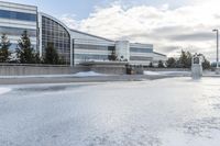 a parking lot covered in snow near a building, and people walking with backpacks