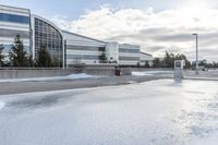 a parking lot covered in snow near a building, and people walking with backpacks