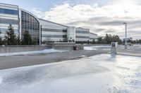 a parking lot covered in snow near a building, and people walking with backpacks