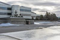 a parking lot covered in snow near a building, and people walking with backpacks