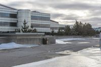 a parking lot covered in snow near a building, and people walking with backpacks