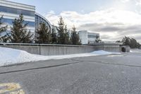 a parking lot covered in snow near a building, and people walking with backpacks