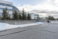 a parking lot covered in snow near a building, and people walking with backpacks