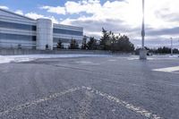 a parking lot covered in snow near a building, and people walking with backpacks