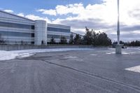 a parking lot covered in snow near a building, and people walking with backpacks