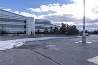 a parking lot covered in snow near a building, and people walking with backpacks