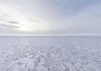 an empty plain covered in snow and ice, with clouds above it to the left