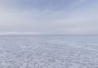 an empty plain covered in snow and ice, with clouds above it to the left