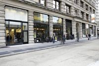 some people are riding bikes down the street by a building or restaurant and other vehicles