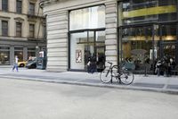 some people are riding bikes down the street by a building or restaurant and other vehicles