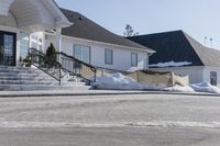 a house with some snow in the front yard and on the sidewalk near the stairs