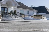 a house with some snow in the front yard and on the sidewalk near the stairs