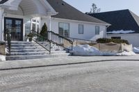 a house with some snow in the front yard and on the sidewalk near the stairs