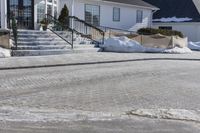 a house with some snow in the front yard and on the sidewalk near the stairs