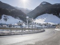 a person is riding their bike down the snow covered road of a mountain village in the winter