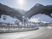 a person is riding their bike down the snow covered road of a mountain village in the winter
